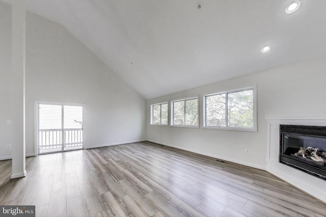 unfurnished living room featuring a glass covered fireplace, vaulted ceiling, recessed lighting, and wood finished floors