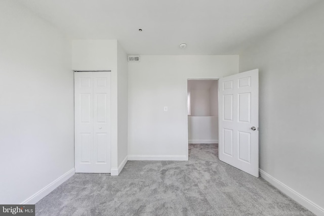unfurnished bedroom featuring carpet floors, baseboards, a closet, and visible vents