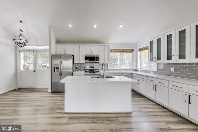 kitchen with decorative backsplash, a sink, light countertops, lofted ceiling, and stainless steel appliances