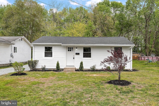 ranch-style house with entry steps, roof with shingles, and a front yard