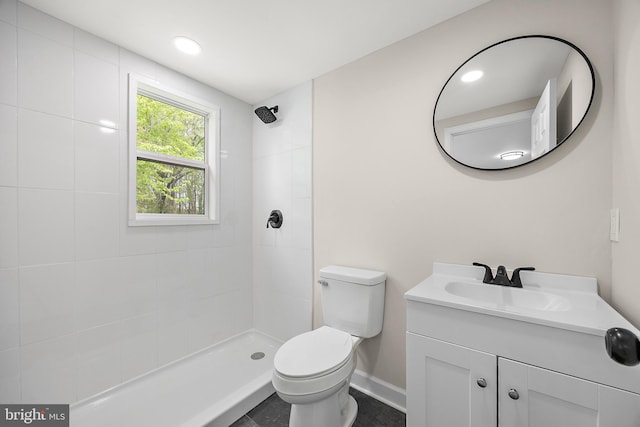 full bath with a tile shower, vanity, toilet, and baseboards