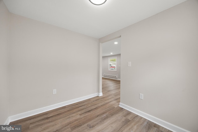 empty room with recessed lighting, wood finished floors, a baseboard radiator, and baseboards