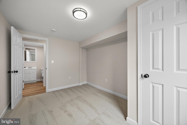 unfurnished bedroom with carpet flooring, baseboards, and a sink