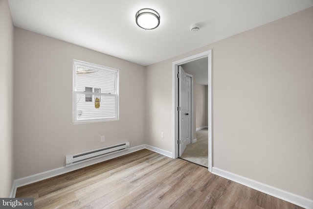 unfurnished bedroom with baseboard heating, baseboards, and wood finished floors