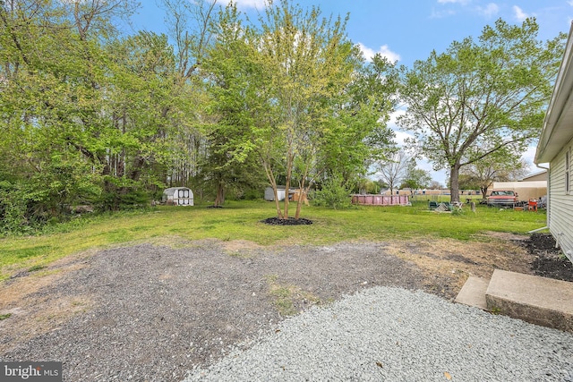 view of yard with fence, a storage unit, and an outbuilding