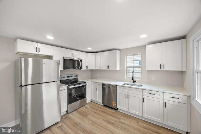 kitchen with light countertops, appliances with stainless steel finishes, white cabinetry, and a sink