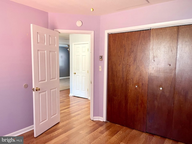 unfurnished bedroom featuring light wood-style floors, a closet, and baseboards