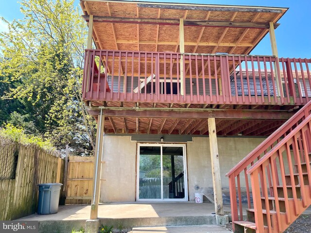 rear view of house featuring fence, stairs, a deck, and a patio
