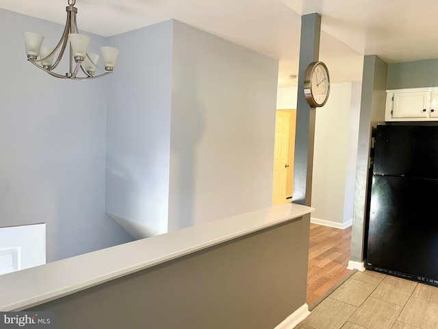 interior space featuring white cabinets, light countertops, freestanding refrigerator, pendant lighting, and a notable chandelier