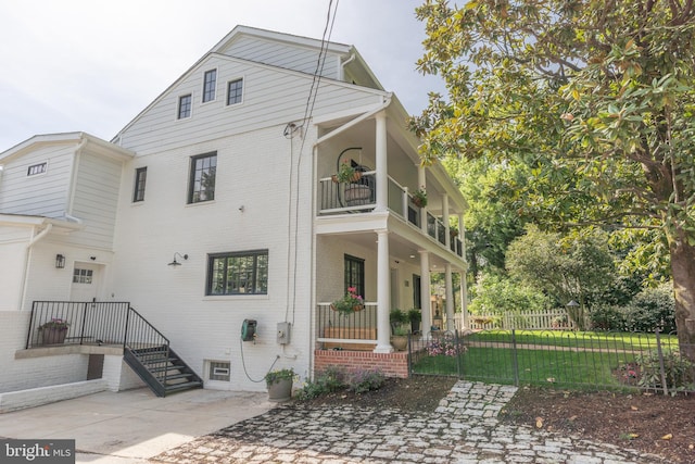 view of front of property featuring fence, a balcony, and brick siding