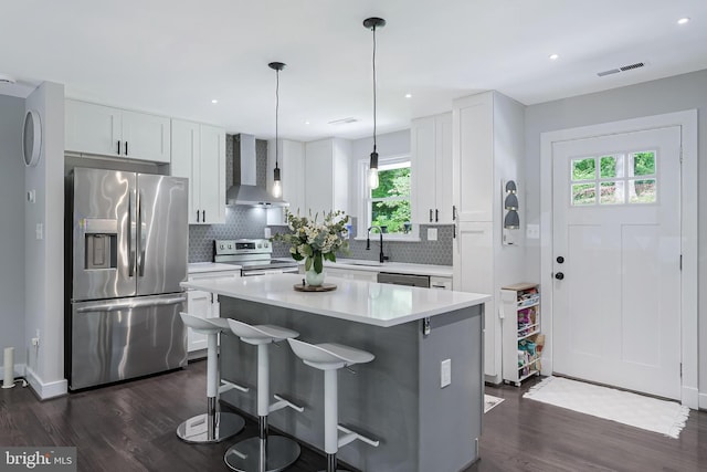kitchen with appliances with stainless steel finishes, wall chimney exhaust hood, plenty of natural light, dark wood-style floors, and recessed lighting