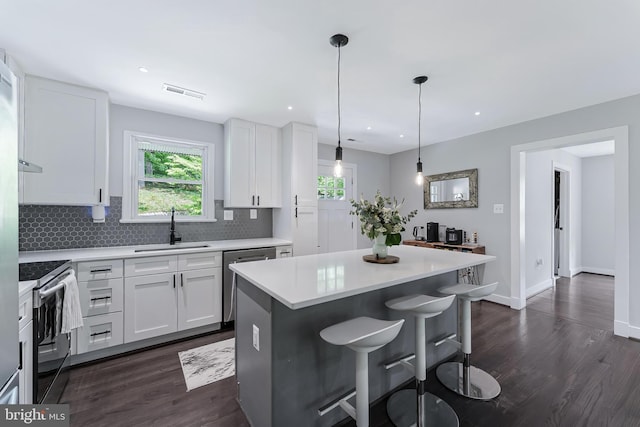 kitchen featuring a sink, stainless steel appliances, dark wood-style floors, light countertops, and recessed lighting