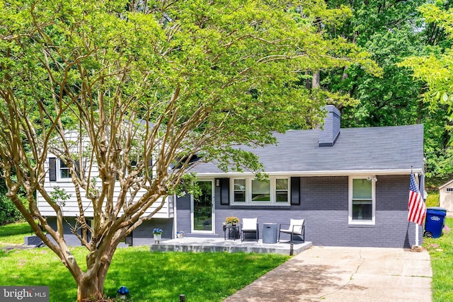 view of front of home featuring brick siding, a chimney, and a front yard
