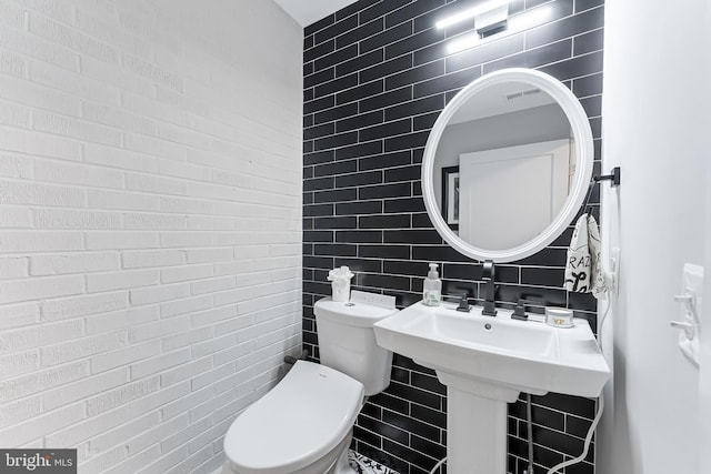 half bath featuring tile walls and toilet