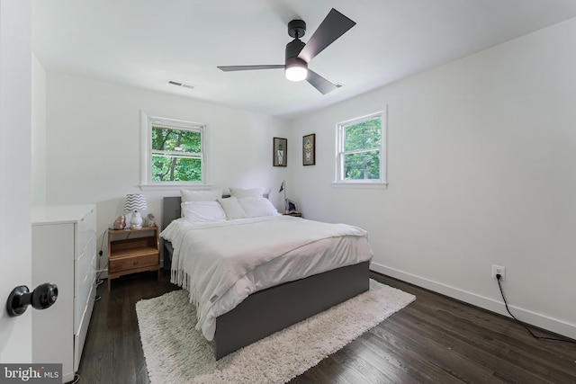 bedroom featuring multiple windows, dark wood-style floors, baseboards, and a ceiling fan
