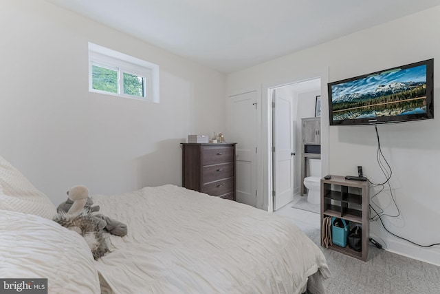 bedroom with light colored carpet, ensuite bathroom, and baseboards