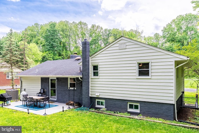 rear view of house with a yard, a patio, a chimney, and central air condition unit