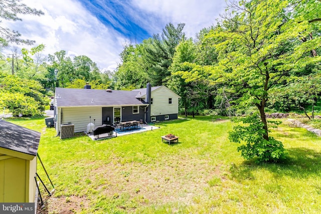 rear view of property featuring an outdoor fire pit, a patio area, a lawn, and a chimney