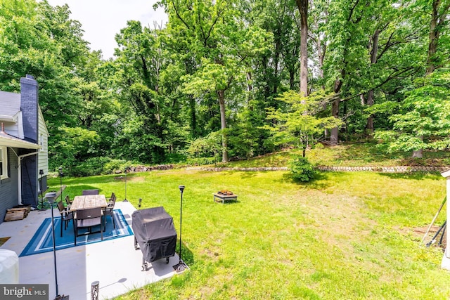 view of grassy yard with an outdoor fire pit, a patio area, and outdoor dining area