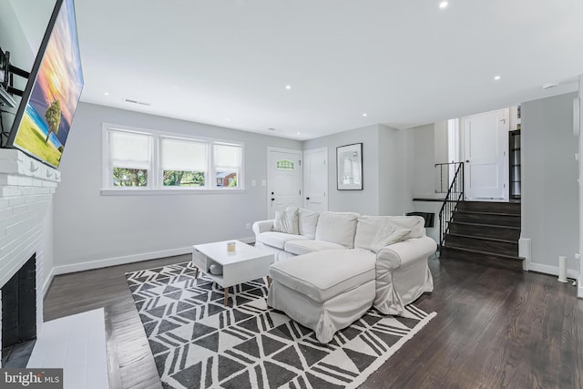 living room featuring dark wood-type flooring, a brick fireplace, baseboards, stairway, and recessed lighting