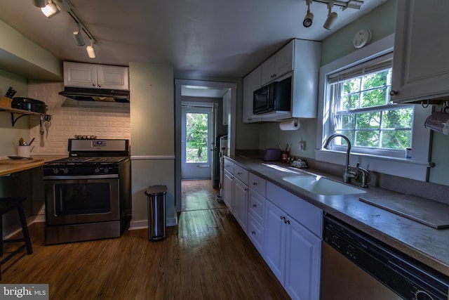 kitchen with a sink, stainless steel appliances, a healthy amount of sunlight, track lighting, and white cabinets