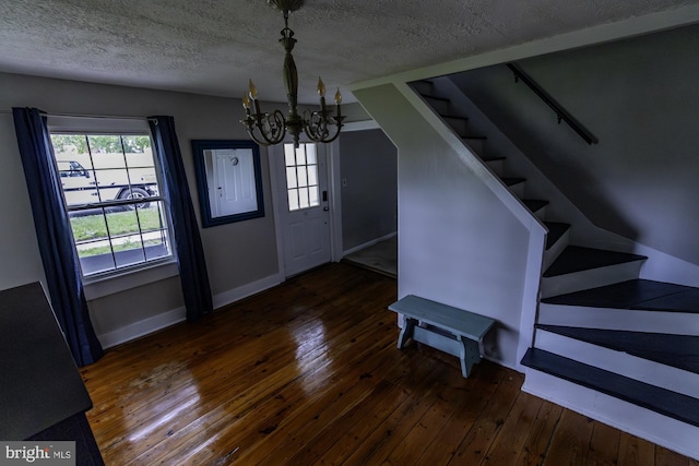 foyer featuring a notable chandelier, wood-type flooring, a textured ceiling, and stairway