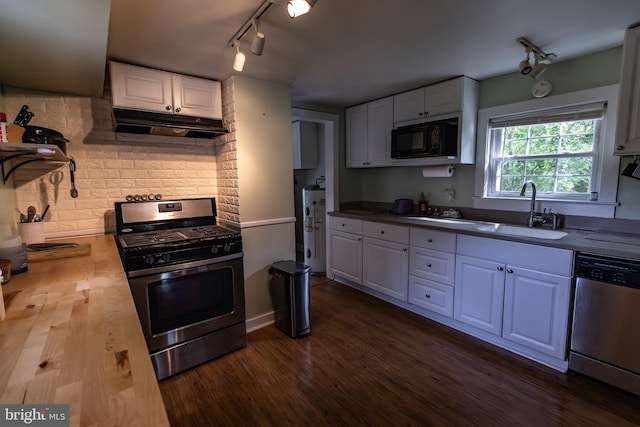 kitchen with a sink, stainless steel appliances, track lighting, dark wood-type flooring, and under cabinet range hood