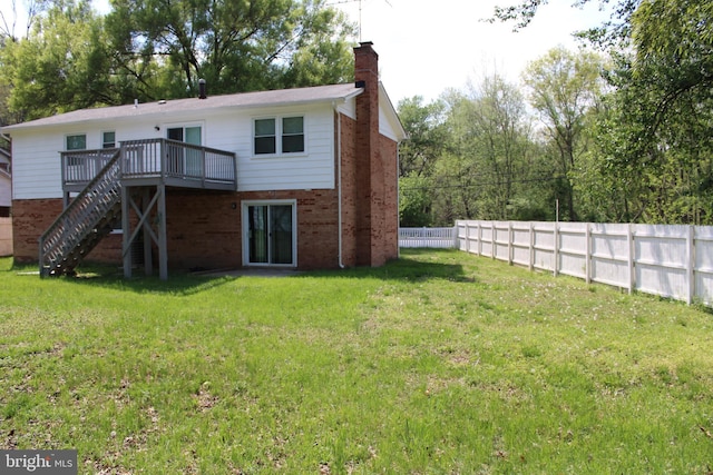 rear view of house featuring a chimney, fence, a yard, brick siding, and a deck