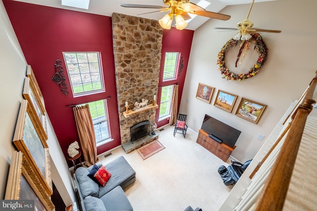 carpeted living room featuring a fireplace, visible vents, a ceiling fan, and high vaulted ceiling