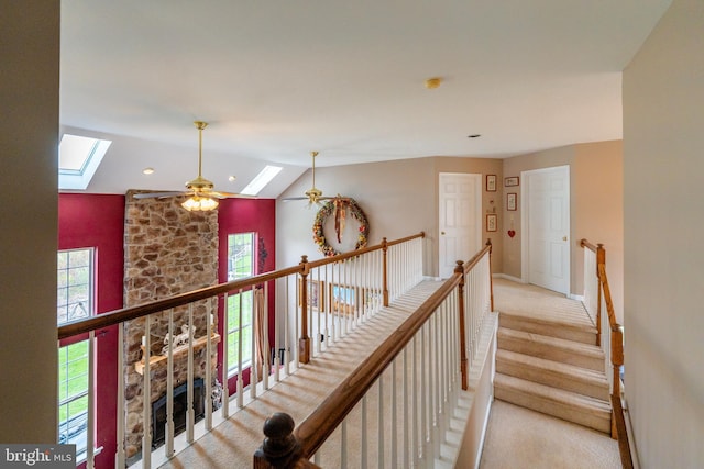 hall featuring carpet flooring, lofted ceiling with skylight, baseboards, recessed lighting, and an upstairs landing