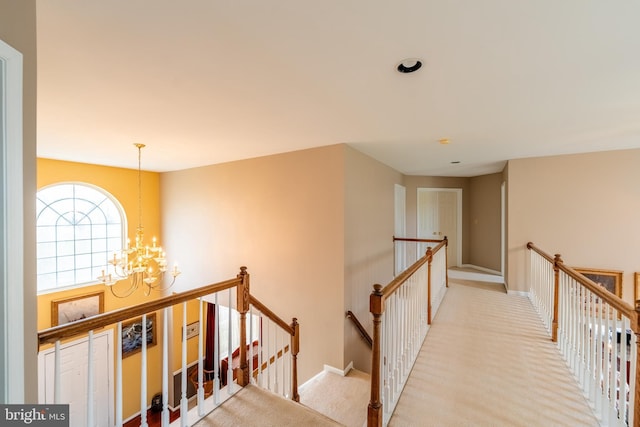 corridor with baseboards, an inviting chandelier, an upstairs landing, and carpet