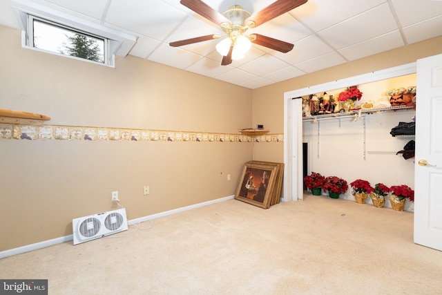 interior space with carpet, ceiling fan, a drop ceiling, and a closet