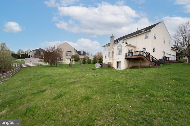 view of yard with a wooden deck, stairs, and fence