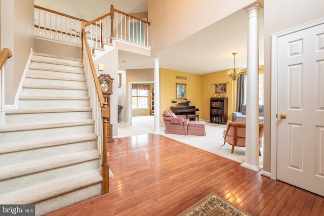 stairs with visible vents, baseboards, an inviting chandelier, ornate columns, and wood-type flooring