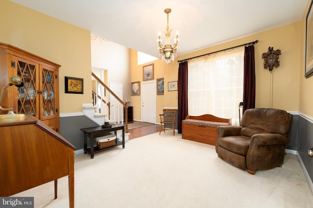 sitting room with a chandelier, carpet flooring, and stairs