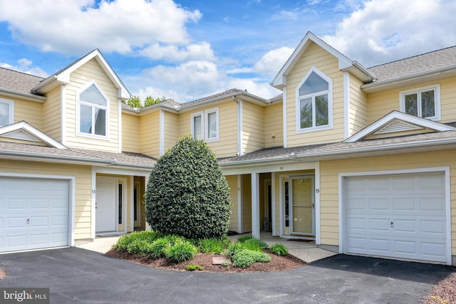 view of property with a garage, roof with shingles, and aphalt driveway
