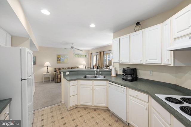 kitchen featuring a peninsula, a sink, open floor plan, dark countertops, and white appliances