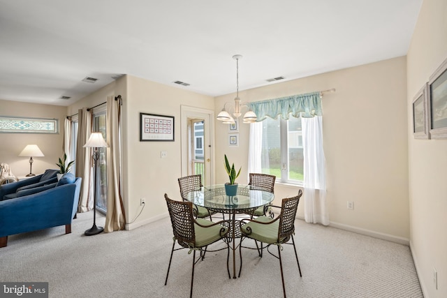 dining space featuring light colored carpet, a notable chandelier, visible vents, and plenty of natural light