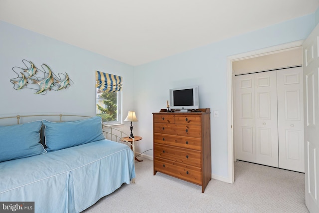 bedroom with a closet, baseboards, and light carpet