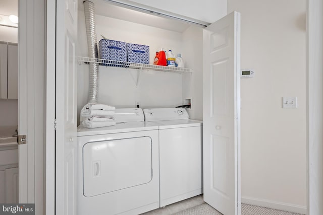 washroom featuring washing machine and clothes dryer, laundry area, and baseboards