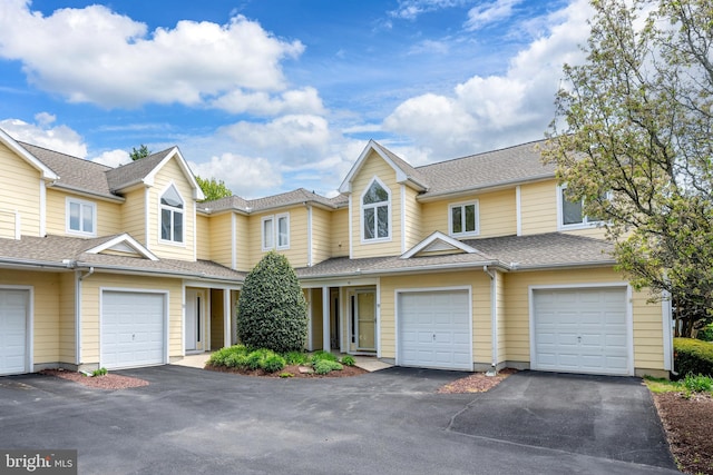 townhome / multi-family property with a shingled roof and driveway