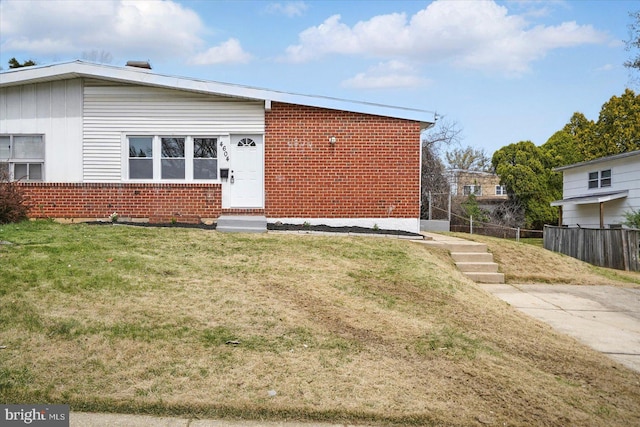 view of front of house featuring brick siding, a front lawn, fence, and board and batten siding