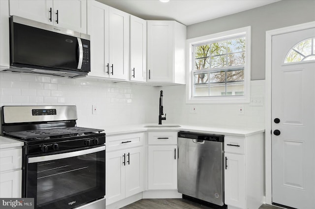 kitchen with white cabinets, stainless steel appliances, light countertops, and a sink