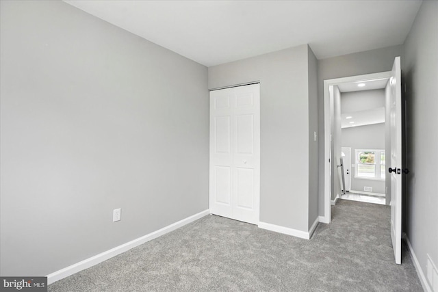 unfurnished bedroom featuring baseboards, carpet flooring, and a closet