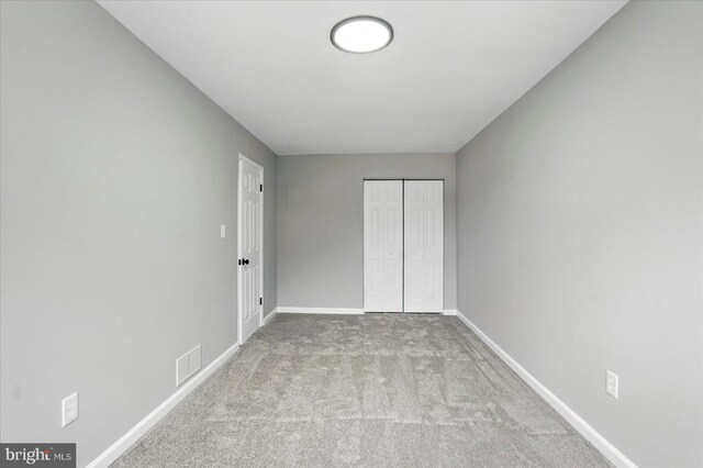 unfurnished bedroom with baseboards, visible vents, carpet floors, and a closet