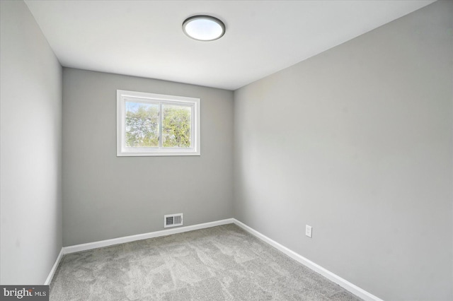 carpeted spare room featuring baseboards and visible vents