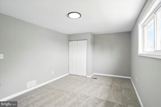 unfurnished bedroom featuring baseboards, a closet, visible vents, and carpet