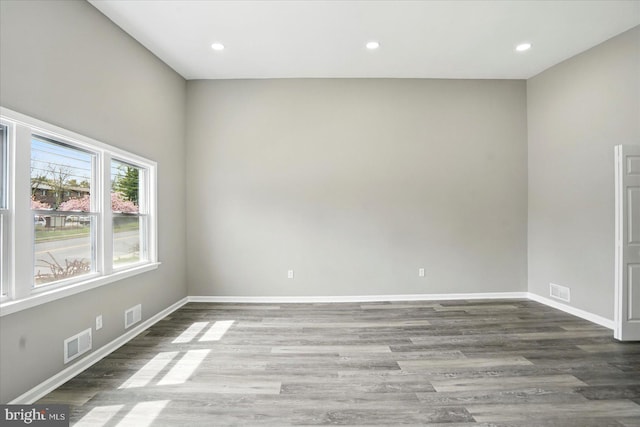 unfurnished room with baseboards, wood finished floors, and visible vents