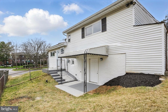 rear view of house featuring fence and a yard