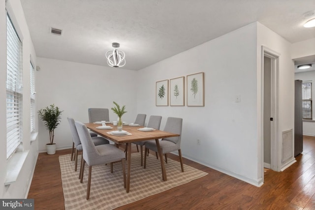dining area with baseboards, visible vents, wood finished floors, and a chandelier
